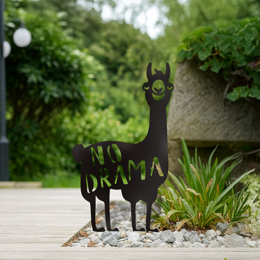 Schwarzer Gartenstecker in Alpakaform mit „No Drama“-Schriftzug steht dekorativ in einem Kiesbeet neben Terrasse und Pflanzstein im Grünen.