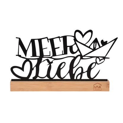 Freigestellter schwarzer Deko-Aufsteller mit dem Schriftzug „Meer Liebe“, verziert mit Herz und Papierboot, auf einem rechteckigen Holzsockel mit UNUS-Logo.