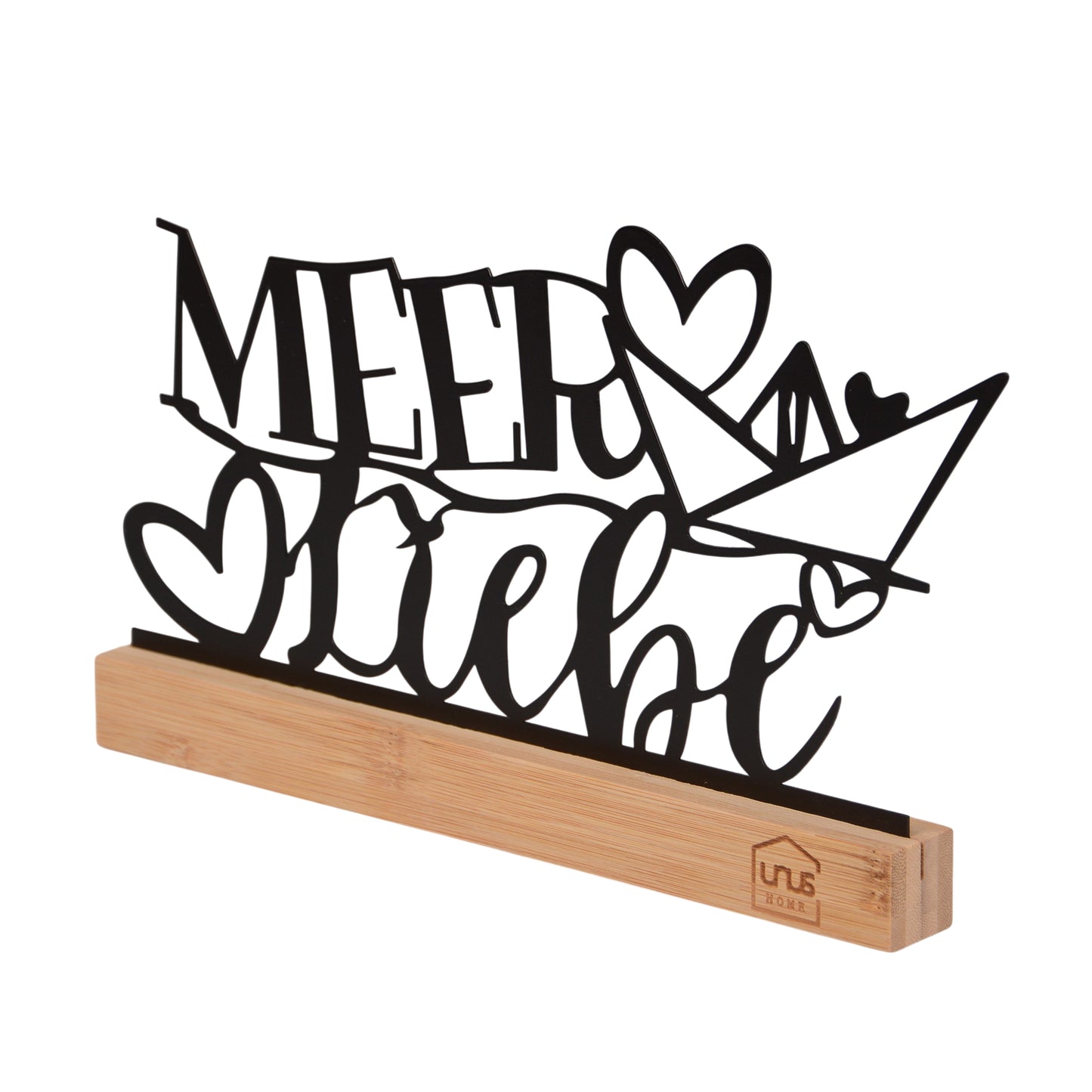 Freigestellter seitlicher Blick auf den schwarzen Schriftzug „Meer Liebe“ mit Herz und Papierboot auf einem naturfarbenen Holzsockel mit UNUS-Logo.