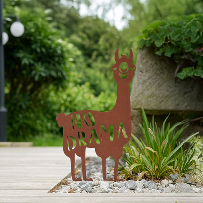Rostfarbener Gartenstecker in Alpakaform mit Schriftzug „No Drama“ steckt dekorativ in einem Kiesbeet neben einer Terrasse im Grünen.
